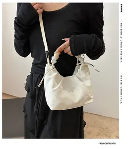 Detail of white textured shoulder bag with chic translucent bead handle and crossbody strap