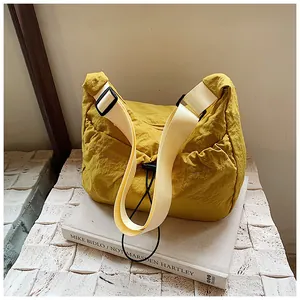 Detail of a ginger yellow pleated tote bag featuring adjustable strap and drawstring closure