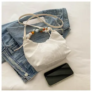 Detail of white marble pattern handbag with colorful beaded handle on denim jacket