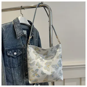 Close-up of elegant butterfly embroidery on a white tote bag with golden hardware