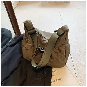Detail of olive green nylon crossbody tote with adjustable strap and drawstring design