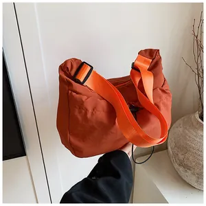 Detail of caramel crescent tote bag with bright orange strap and elastic drawstring