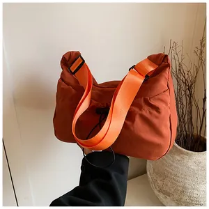 Detail view of rust red tote bag with adjustable bright orange nylon shoulder strap
