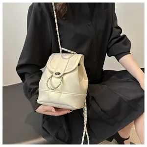 Detail eines cremeweißen Rucksacks mit Metallverschluss an einem Modell im Hemdkleid