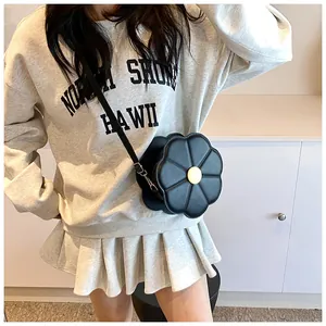 Détail d'un sac à bandoulière en forme de fleur noire en similicuir avec boucle dorée