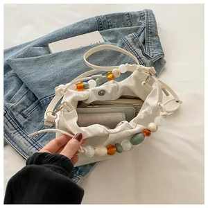 White pleated cloud bag detail showing interior space, magnetic closure, and colorful beads
