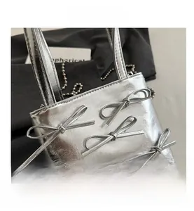 Close-up of silver mini tote bag with decorative bows and metallic bead chain strap
