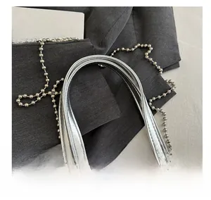 Detail of silver metallic tote bag featuring a bow design and chain handle handles