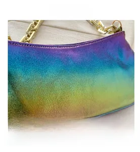 Close-up of iridescent leather underarm bag featuring a chunky gold chain and stitching