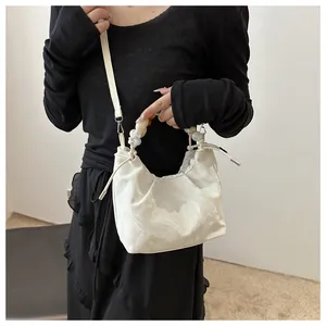 Detail of marble pattern shoulder bag with colorful beaded handle and ruched texture