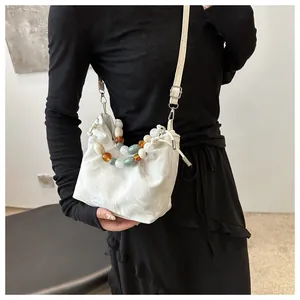 Detail view of white marble bucket bag with beaded handle and silver hardware