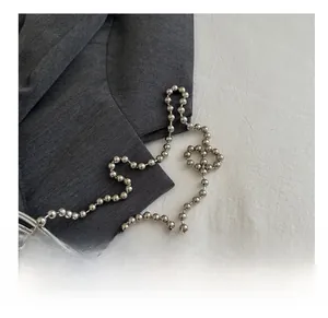 Close-up of sleek silver metallic ball chain strap on a glossy mirror surface handbag