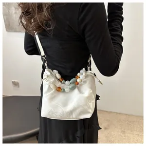 Detail of marble pattern pleated bag with colorful bead handles and drawstring closure