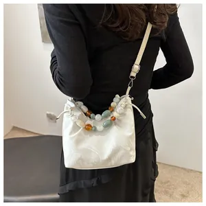 Detail of white marble pattern crossbody bag featuring vibrant acrylic bead chain and strap