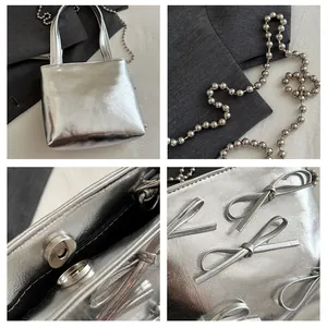 Detail of silver metallic handbag showing bead chain strap, magnetic buckle and bow decor