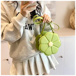 Gros plan d'un sac bandoulière en forme de fleur vert clair porté sur un sweat gris