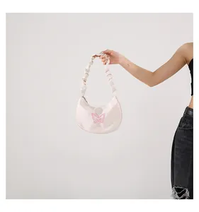 Close-up of butterfly embroidery and ruched strap on the cream crescent shoulder bag