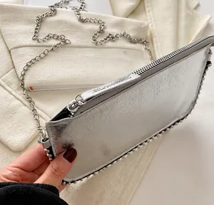 Detalle del bolso plateado para móvil con cremallera suave y correa de cadena metálica