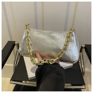 Close-up of a metallic silver underarm bag with thick gold chain strap texture