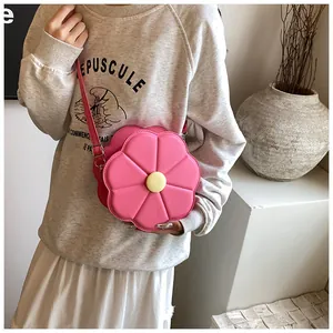 Détail d'un sac à bandoulière rose en forme de fleur avec bouton jaune et lanière en cuir