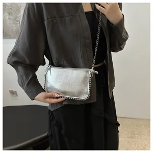 Detalle del bolso plateado metalizado con remaches y una elegante correa de cadena