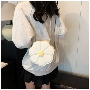 Gros plan d'un sac bandoulière en forme de fleur blanche porté par un mannequin en intérieur