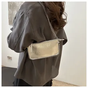 Detail of silver metallic shoulder bag with stud edges and sleek metal chain strap