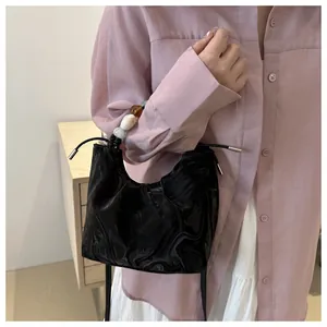 Detail of black glossy pleated cloud bag with colorful translucent bead chain strap