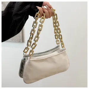 Detail of cream white smooth and metallic silver cracked leather bags with gold chain