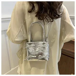 Close-up of a silver bow mini tote bag with metallic texture and beaded chain strap