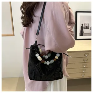 Detail of black pleated bucket bag with decorative colorful resin bead handle and drawstring