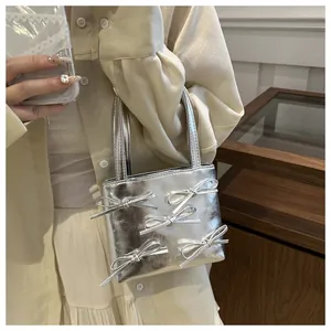 Detail of silver metallic mini tote bag with decorative 3D bows and dual handles