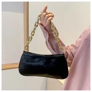 Detail of black matte leather underarm bag featuring a bold gold chunky chain strap