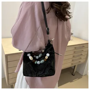 Detail of a black pleated leather cloud bag with vibrant colorful beads on the handle