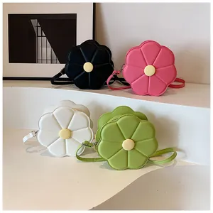 Détail de sacs à bandoulière floraux en noir, rose, blanc et vert sur socle design
