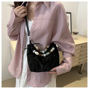 Detail of black pleated crossbody bag featuring vibrant marble-style colorful bead handle