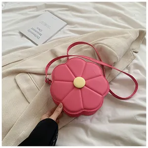 Gros plan du sac bandoulière en cuir en forme de fleur rose avec centre jaune sur fond beige