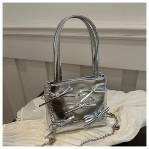 Detailed close-up of a silver metallic mini tote bag with bow decorations and chain strap