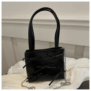 Close-up of black PU leather handbag featuring 3D bow ties and silver bead chain detail