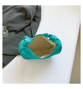 Top view of blue-green pleated shoulder bag with interior zipper and beige lining detail