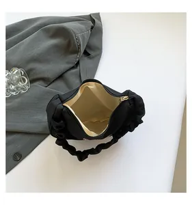 Internal view of black ruched shoulder bag showing beige lining and smooth zipper detail