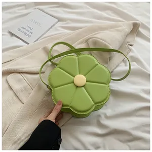 Détail du sac bandoulière vert en forme de fleur avec centre jaune sur blazer blanc