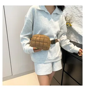 Dettaglio del marsupio trapuntato in nylon marrone con cinturino indossato dal modello