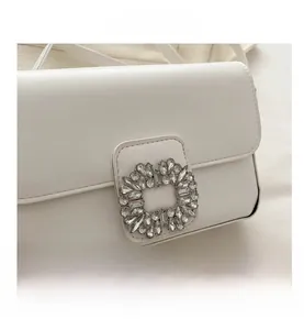 Close-up of a white lychee leather handbag featuring a luxury square rhinestone buckle