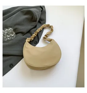 Detail of khaki crescent shoulder bag featuring ruched handle and leather texture