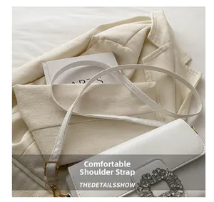 Detail of a white leather shoulder bag with adjustable strap and diamond buckle