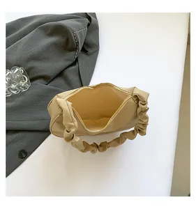 Macro view of beige pleated shoulder bag with metallic zipper and spacious interior