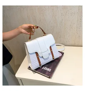 Detalle de bolso montura blanco y púrpura con grabado de cocodrilo y remaches dorados