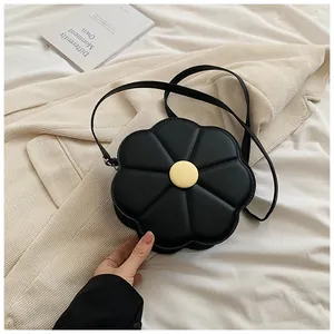 Sac à bandoulière fleur noire avec centre jaune posé sur un trench-coat élégant