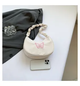 Detail view of white shoulder bag with pink butterfly embroidery and pleated strap style